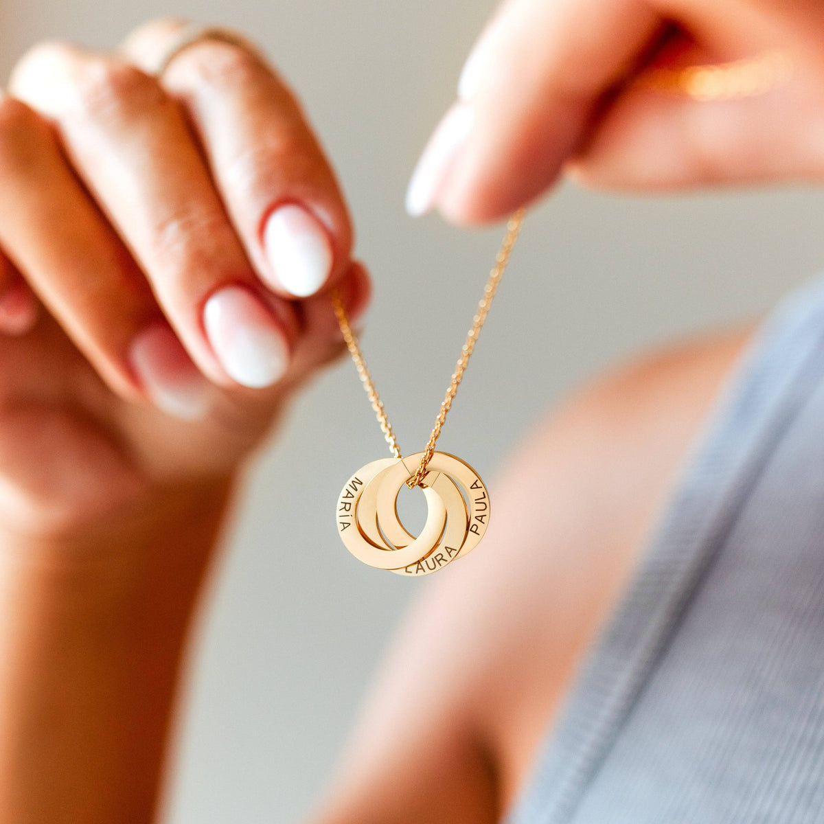 Amity necklace with three gold plated rings, held in hands. Names shown are examples.
